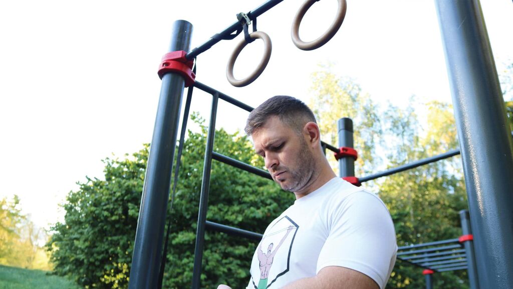 Ivan performing a bodyweight workout under gymnastics rings in an outdoor calisthenics park in Dublin, Ireland