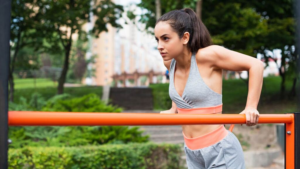 Woman practicing calisthenics dips during outdoor training