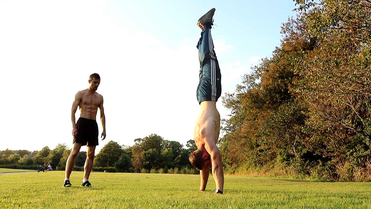 Calisthenics Ireland coaches performing a handstand during outdoor training in a public park