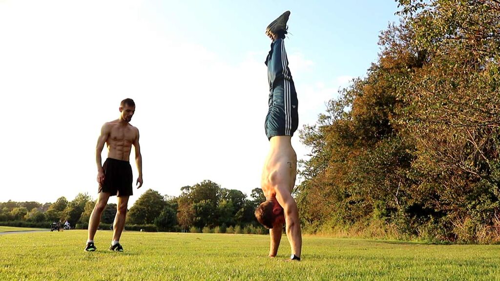 Calisthenics Ireland coaches performing a handstand during outdoor training in a public park